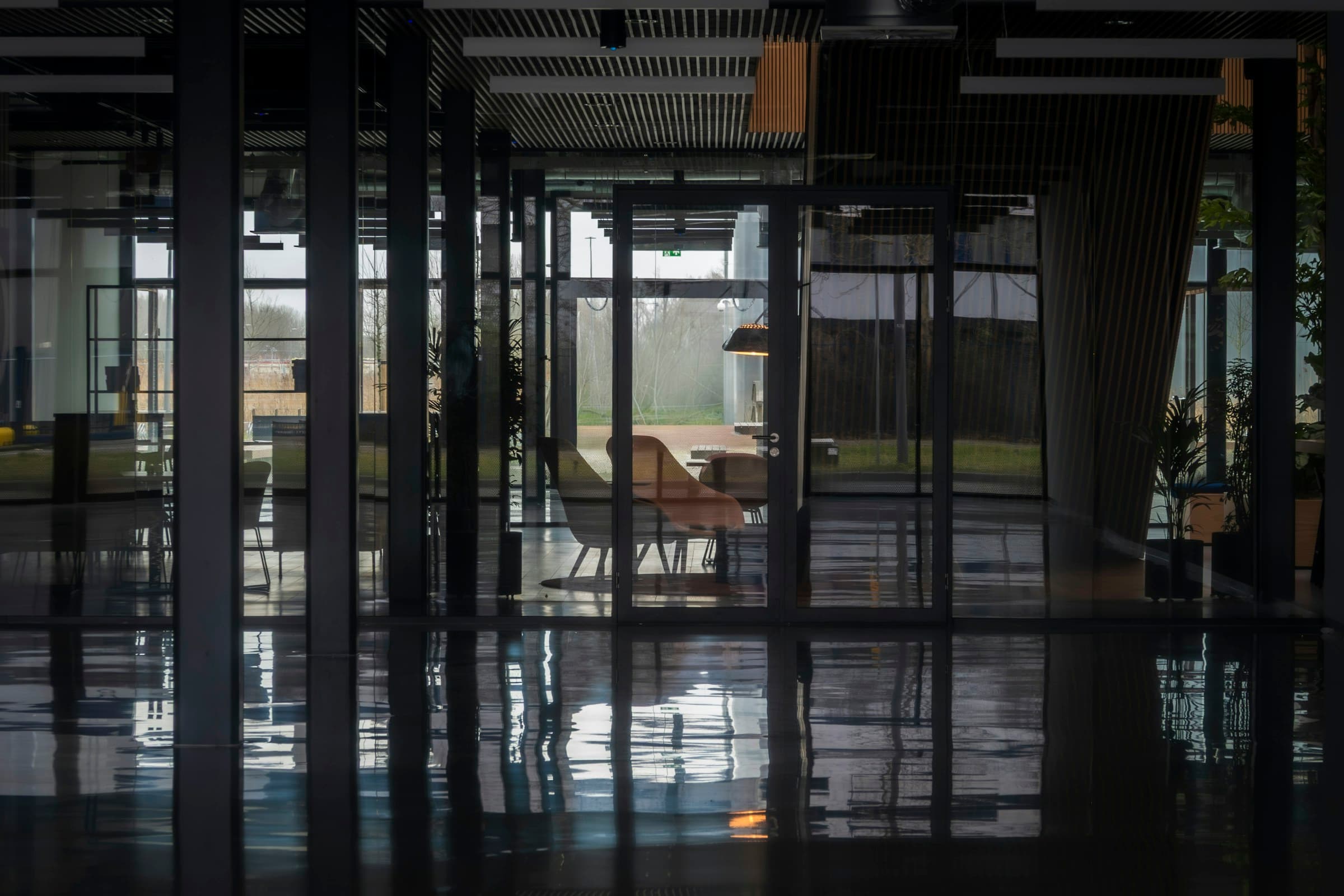 A contemporary commercial office interior with glass walls and reflections.